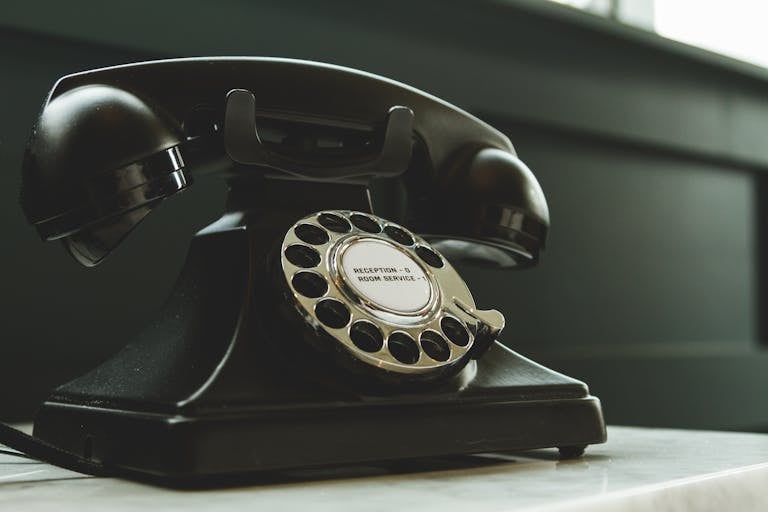 Classic black rotary phone on hotel reception desk, evoking nostalgia and vintage charm.