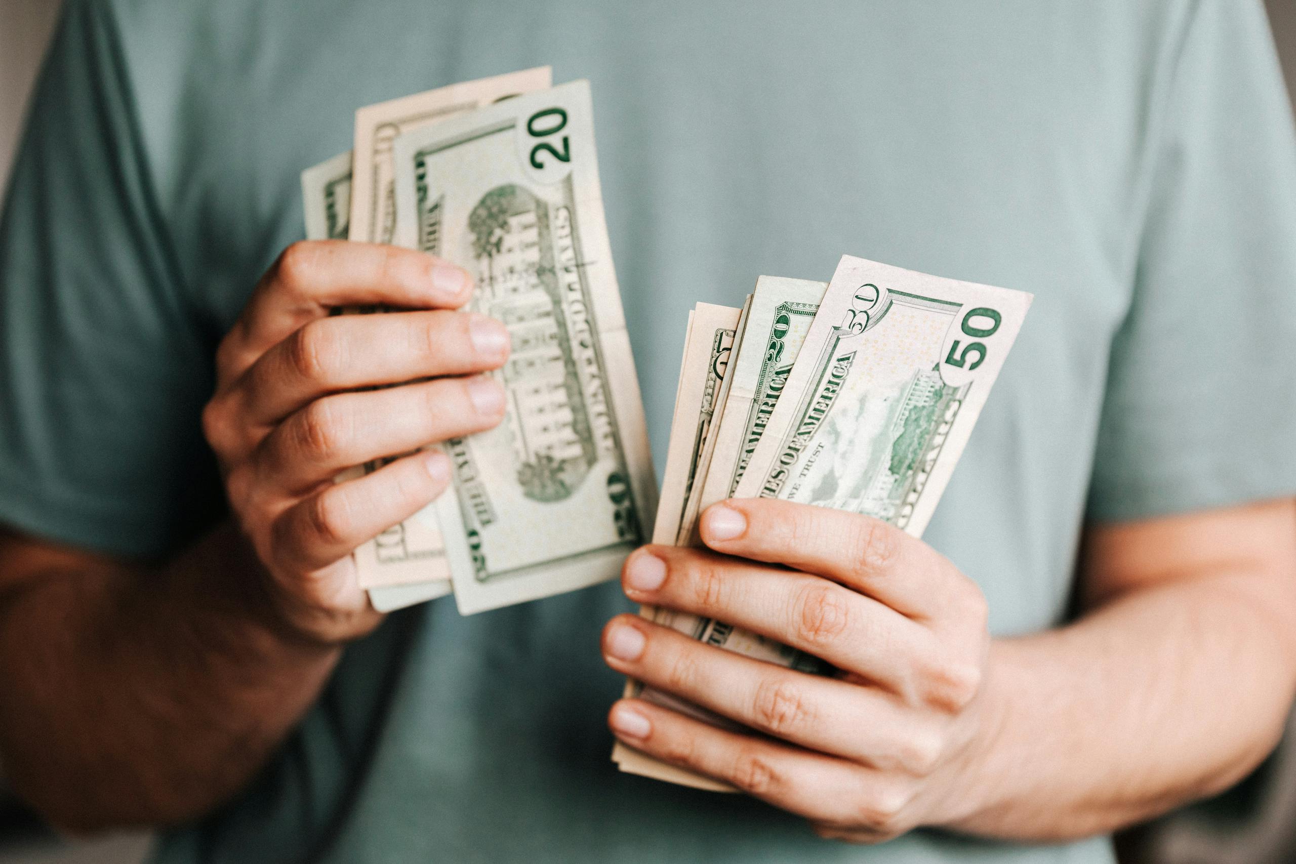 Close-up of a person counting US dollar bills indoors. Financial concept.