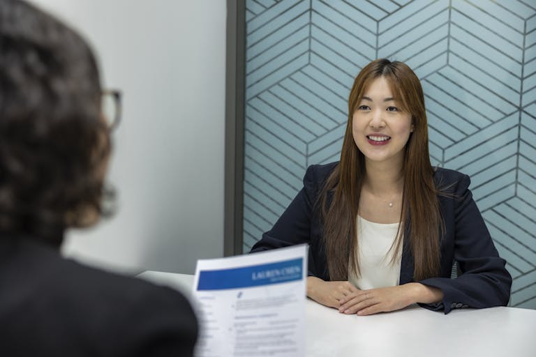 Young woman in a business meeting with an interviewer, showcasing confidence and professionalism.